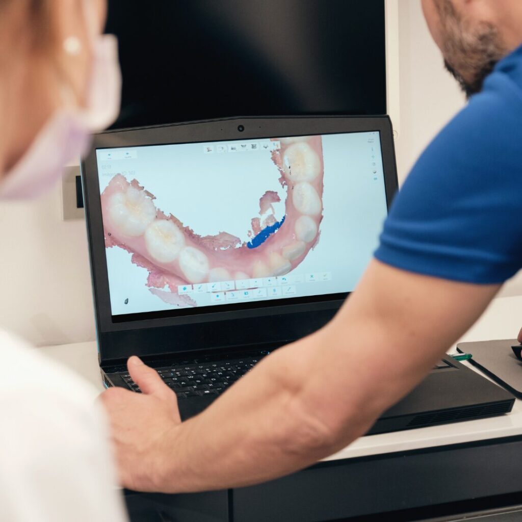 Lekarz analizuje trójwymiarowy skan 3D zębów na ekranie komputera.